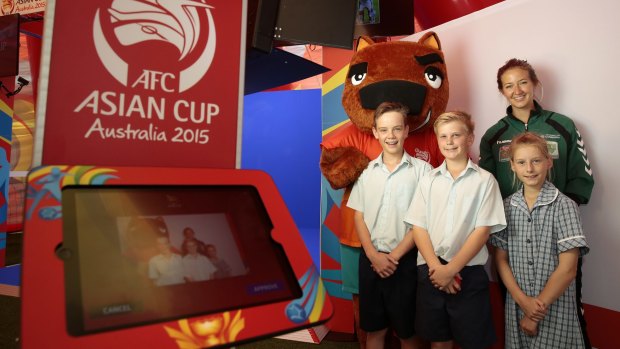 AFC Asian Cup mascot Nutmeg, Canberra United player Grace Gill, front from left, Trinity Christian School year 7 student Ben Carling, year 6 student Tim Noack and year 4 student Mali Vanderstoep at the Join the Team photo booth at the AFC Asian Cup Football Fan Park at Garema Place.