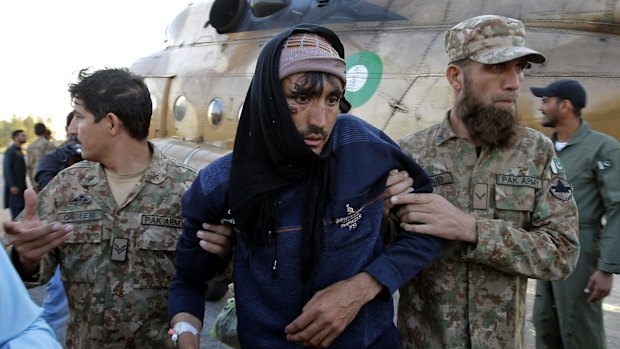 Pakistani soldiers help a man who was injured in Monday's earthquake after he was evacuated to Peshawar airbase in Pakistan, on Tuesday.