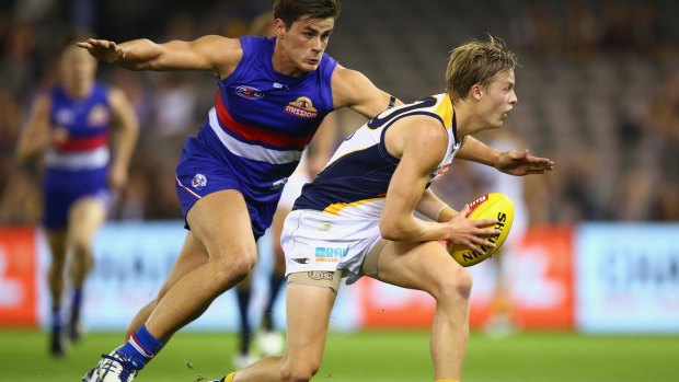 Arms up: West Coast's Jackson Nelson is pressured by Tom Boyd of the Bulldogs at Etihad Stadium on Saturday night. 