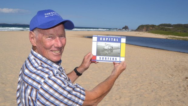 Ian Ingram with his new book Capital Surfers on Narooma main surf beach, the exact location where he was photographed with his VW Beatle in 1964, featured on the front cover.