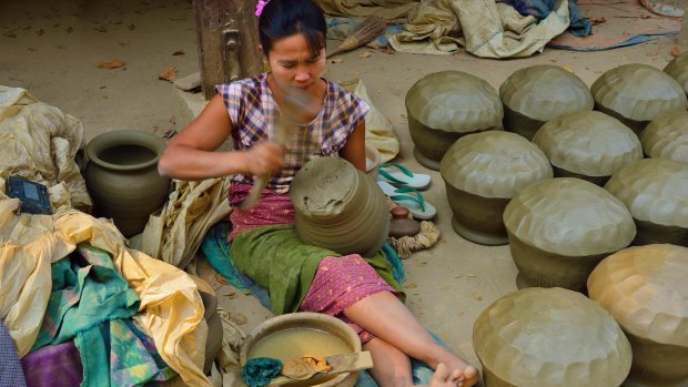 A woman beats clay waterpots into shape with  a wooden paddle at Yandabo village  near Mandalay.