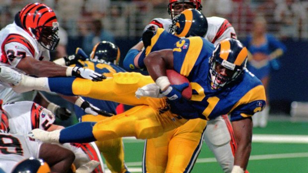 Lawrence Phillips leaps over a mound of players as he scores a touchdown for the Rams against the Cincinnati Bengals in 1996.