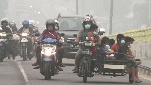 Motorists ride on a road as thick haze from wildfires blankets the city of Pekanbaru, Riau province, Indonesia.