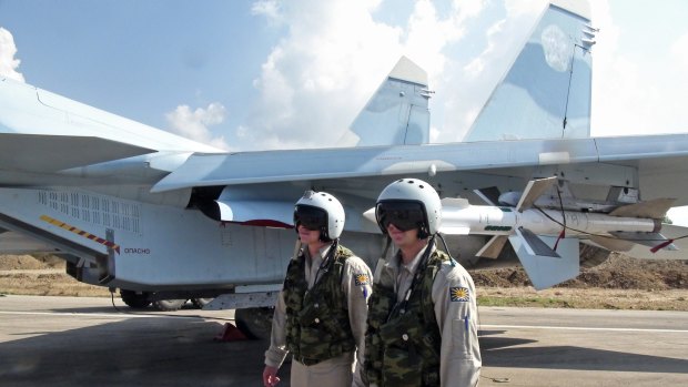 Russian pilots stand beside their Su-30 jet fighter at Hmeimim airbase in Syria.