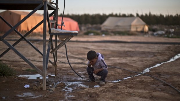 A Syrian refugee child drinks water from a pipe at an informal settlement on the outskirts of Mafraq, Jordan, last month.