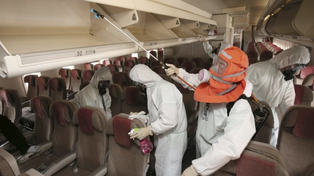 Workers wearing protective gear spray anti-septic solution in an aeroplane at Incheon International Airport, South Korea.