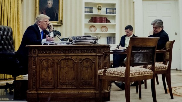 US President Donald Trump speaks on the phone with Australia's Prime Minister Malcolm Turnbull as retired Lieutenant General Michael Flynn, U.S. national security advisor, center, and Steve Bannon, chief strategist for U.S. President Donald Trump wait. 