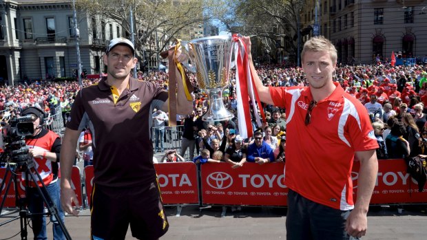 Hawthorn's Luke Hodge and Sydney's Kieren Jack hold up the AFL Premiership Cup during the 2014 parade.
