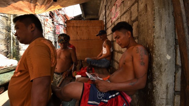 Men drink beer and read the newspapers in one of the alleys of Tondo district in Manila, Philippines. General crime rates have dropped in some barangays in Tondo since Philippine President Rodrigo Duterte's war on drugs campaign started. 