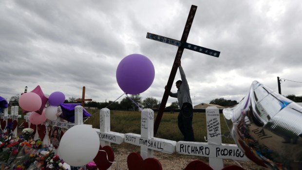 Miguel Zamora stands a cross for the victims of the Sutherland Springs First Baptist Church shooting at a makeshift memorial in the town. Zamora carried the cross for three days to reach the site. 