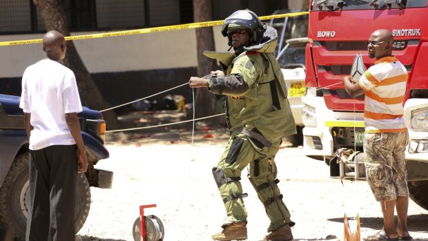 A member of a bomb disposal team prepares the scene before checking the bodies of three women.