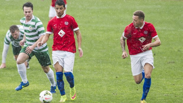 Canberra FC players Thomas James, right, and Muad Zwed, middle, in action as the rain comes down on Sunday afternoon.