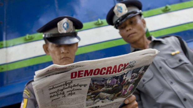 Police officers read a copy of the newspaper, Democracy Today, in Yangon on Wednesday.