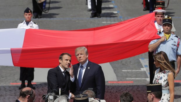 French President Emmanuel Macron talks with US President Donald Trump next to a huge French flag after the Bastille Day parade in Paris.
