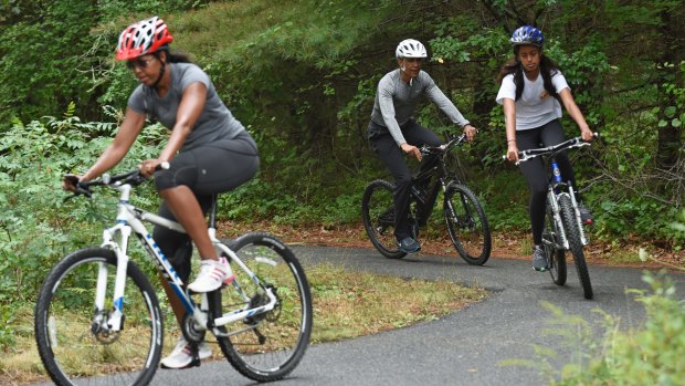 From left: Michelle Obama, Barack Obama and their eldest daughter Malia ride their bikes while on holidays in Martha's Vineyard during his presidency.