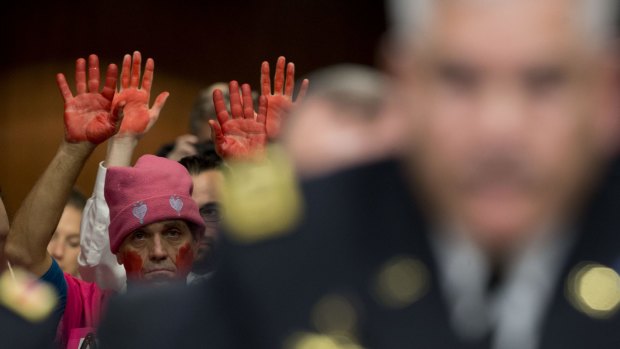 A demonstrator from Code Pink raises his hands as General John Campbell, commander of US forces in Afghanistan, right, speaks during a Senate hearing in Washington last week.