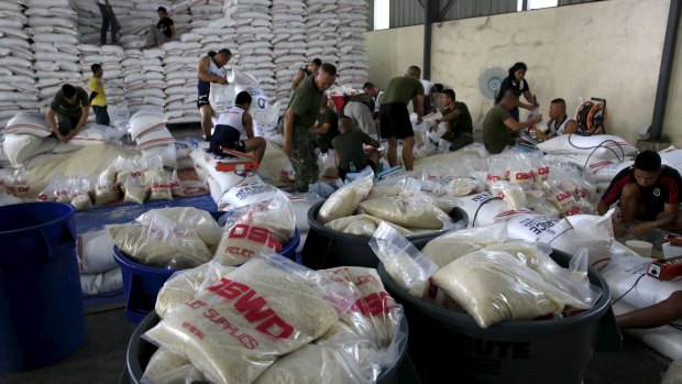 Members of the Armed Forces of the Philippines help out volunteers repacking food rations for victims of Typhoon Nou.