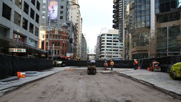 Workers prepare the road surface on Sunday for resealing at the busy intersection on George Street.