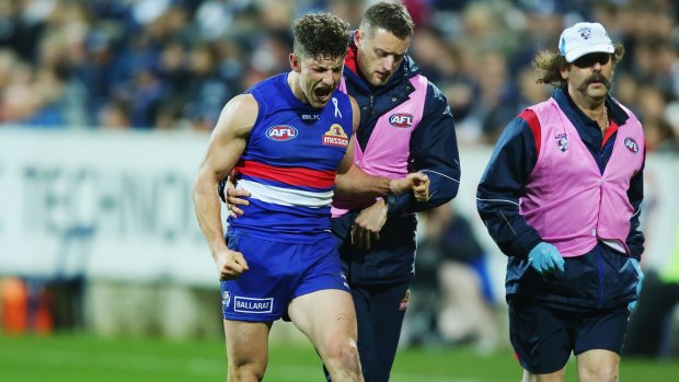 Tom Liberatore is helped from the ground after injuring his ankle against Geelong.