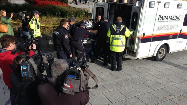 Police and medical personnel move a wounded person into an ambulance at the scene of a shooting at the National War Memorial in Ottawa.