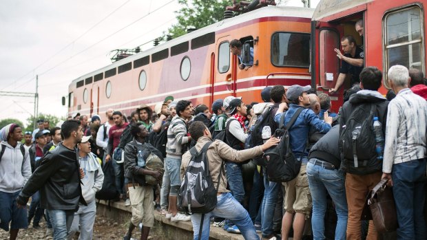 Migrants try to board a train in Demir Kapija on Thursday.