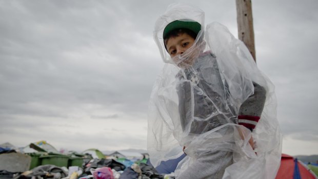 A child wears a plastic cover in the rain in the northern Greek border station of Idomeni on Monday. 