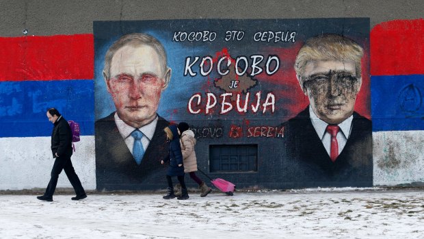People walk by Serb nationalist graffiti depicting Russian President Vladimir Putin and US President Donald Trump in Belgrade.
