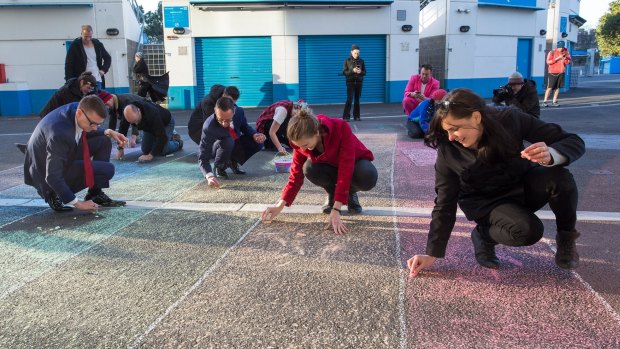Marriage equality activists draw a rainbow flag with chalk outside Margaret Court Arena on Saturday.
