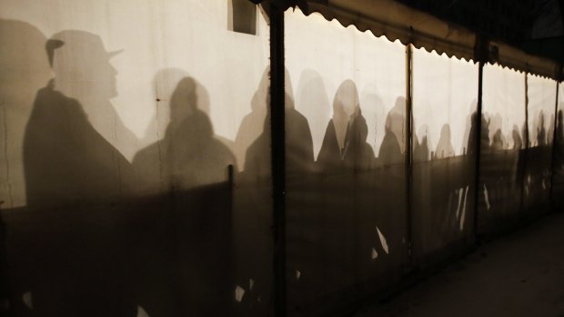 Migrants are silhouetted as they warm themselves inside a waiting tent to get an appointment at the central registration center for refugees and asylum seekers in Berlin on Wednesday.