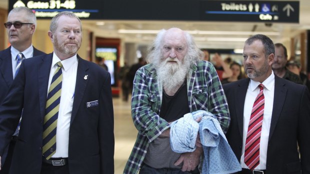 Colin Michael Newey is escorted through Sydney Airport by police after being extradited from South Australia in July 2014.
