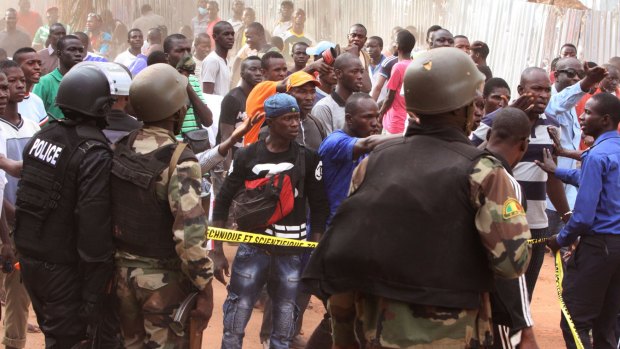 Mali troops try to control a crowd of onlookers near the Radisson Blu hotel, after Islamic extremists armed with guns and grenades stormed it on Friday morning.