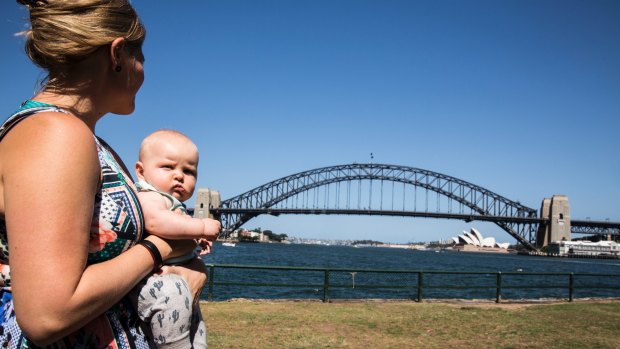 Claudia Tyson holds a friend's baby at Blues Point Reserve, which will be affected by excavation for the Sydney Metro.