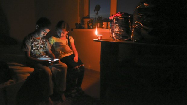 Crimean children play on a mobile phone in candlelight at their home, after a power failure, in a village outside Simferopol, Crimea, on Sunday.
