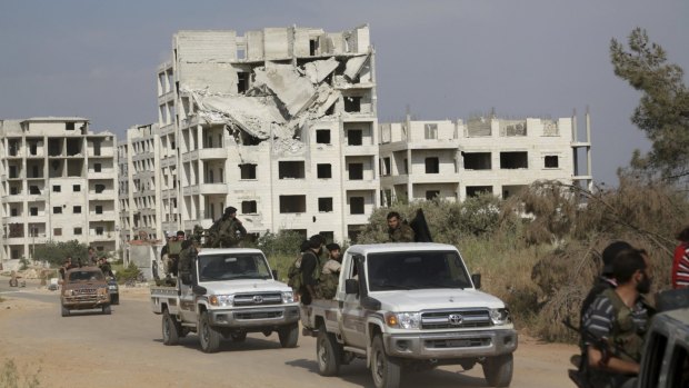 Rebel fighters move in a convoy in the city of Idlib.
