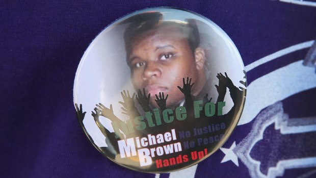 A resident wears a button featuring a picture of teenager Michael Brown, who was killed by police officer Darren Wilson on August 9.