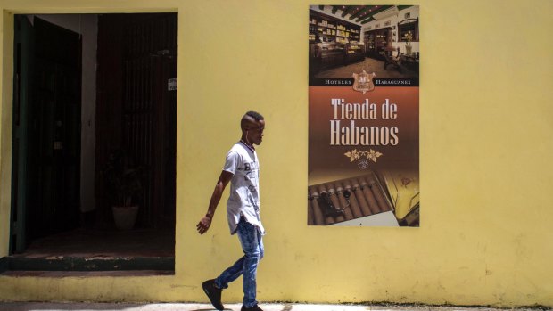 A youth walks beside a cigar store of the Habaguanex company in Old Havana, Cuba.