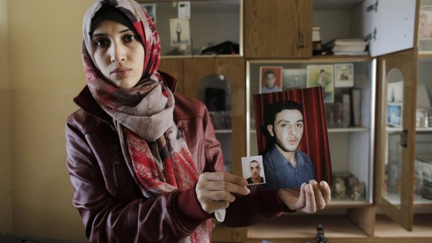 A relative of Ghassan and Udai Abu Jamal, cousins who killed four worshippers in a Jerusalem synagogue, holds their pictures at her home in the Jerusalem district of Jabal Mukabar.