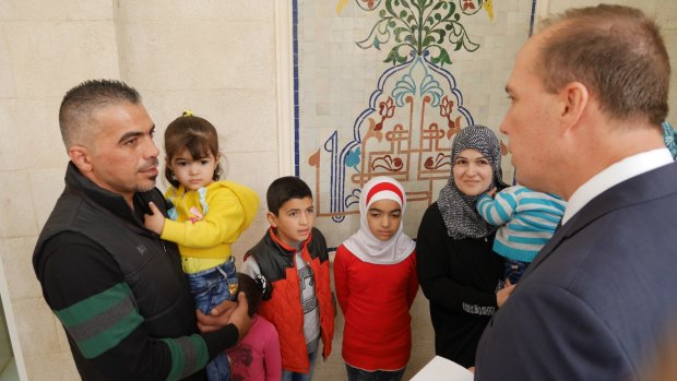 Immigration Minister Peter Dutton hands out a refugee visa to a family earlier this month.