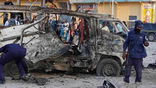 Security forces stand near the wreckage of a minibus at the scene of a car bomb attack in Mogadishu, Somalia on Thursday.