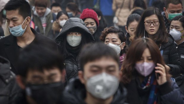 Masked Chinese commuters, many wearing masks, walk to work during heavy pollution on Wednesday. 