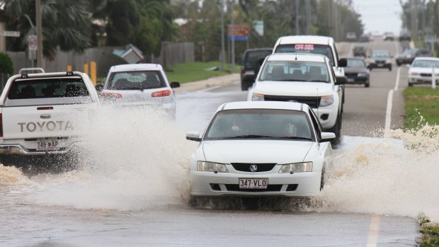 Cars drive through partially flooded roads in Bowen the day after Cyclone Debbie blew through.