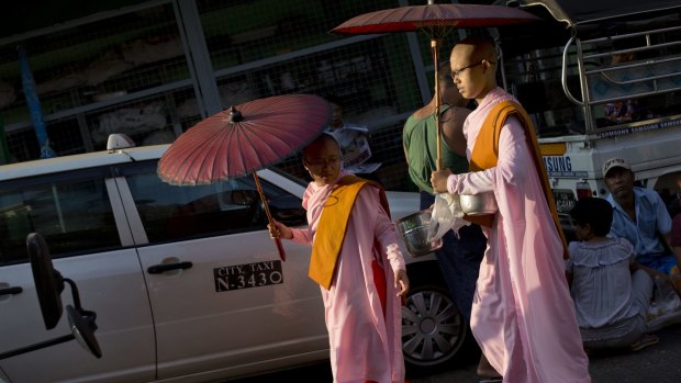 Buddhist nuns walk through a street market collecting alms in Yangon last week. 