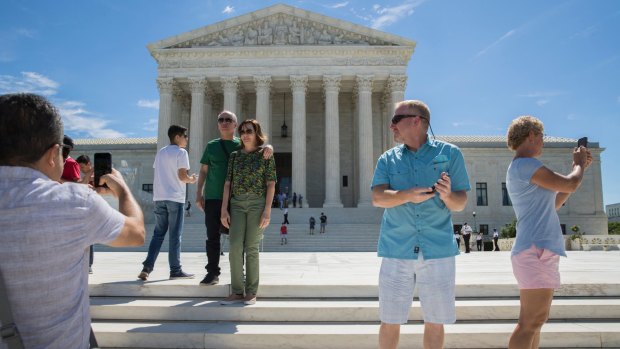 People visit the Supreme Court in Washington on Monday as the court allowed a limited travel ban to take effect until October.