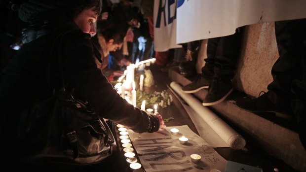 A woman places a candle during a gathering at the Place de la Republique (Republic Square) in Paris following the attack on <i>Charlie Hebdo</i>.