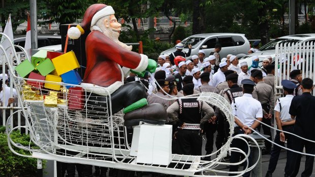 A Santa on a sleigh is seen near a protest against Christmas apparel by members of the hardline Islam Defenders Front in Surabaya.
