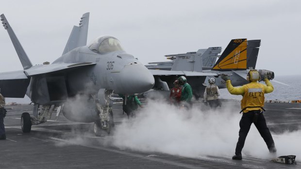 A flight deck director signals a fighter jet to move on the deck of the nuclear-powered aircraft carrier the USS John C. Stennis.