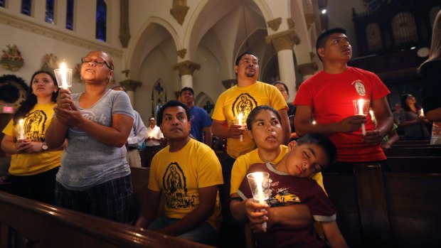 Worshipers pray and sing during a "United To Heal Prayer Vigil" at Cathedral Guadalupe, in honor of the slain police officers in Dallas.