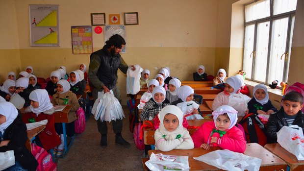 An Islamic State militant distributes bags full of stationery to Iraqi school pupils in Mosul, northern Iraq.  