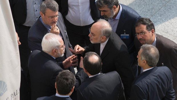 Mohammad Javad Zarif (centre, left) and the head of Iran's atomic energy program Ali Akbar Salehi (centre, right) talk while aides listen after a negotiation session with John Kerry in Lausanne in March this year.