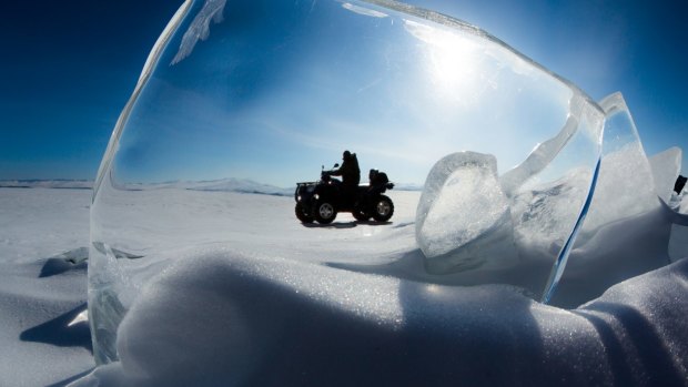 An explorer drives an ATV across Russia's Lake Baikal.